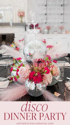 a disco ball centerpiece with pink flowers and feathers