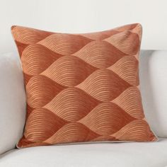 an orange pillow sitting on top of a white couch