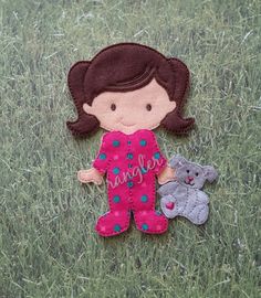 a small doll laying in the grass next to a teddy bear