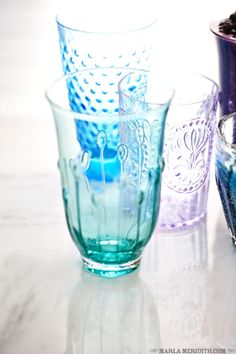 three different colored glass vases sitting on a white counter top next to each other