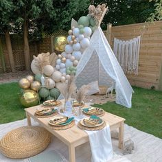 a table set up for a party with balloons, plates and napkins on it