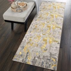 a large rug with yellow and gray designs on it in a living room area next to a couch