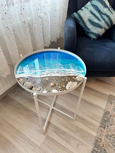 a table with an ocean scene painted on it in front of a chair and window