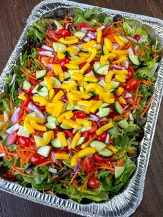 a salad in a foil container on a wooden table