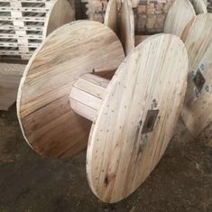 three wooden spools are stacked on top of each other in front of some pallets