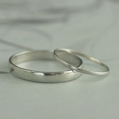 two silver wedding rings sitting on top of a white bed sheet in front of the camera