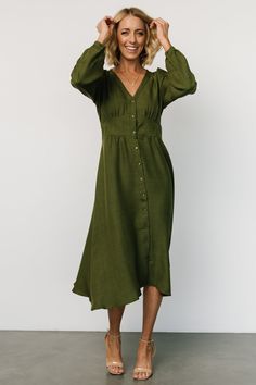 Casual and stylish all in one dress Lightweight linen-like material Olive green color V-neckline Buttoned placard down front of dress Gathering at bust, shoulder yoke, and across back Long sleeves with single buttons at cuffs Upturned, paneled V-waistband with subtle gathering underneath Elastic at back waist Unlined 63% Recycled Polyester, 37% Polyester Trina is 5'6, cup size 32D, size 2 and is wearing size S Green V-neck Maxi Dress With Button Closure, V-neck Midi Dress With Button Closure For Brunch, Green Button Closure Midi Dress For Spring, Green Midi Dress With Button Closure For Spring, Green Maxi Dress With Button Closure, Fitted V-neck Linen Dress With Buttons, Green Fitted Button-up Maxi Dress, Green Long Sleeve V-neck Dress For Brunch, Chic Green Linen Midi Dress