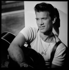 black and white photograph of a young man playing an acoustic guitar