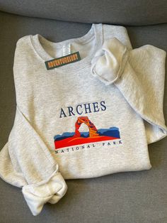 - Arches National Park Embroidered Hoodie - Perfect gift for nature lovers, adventurers, or anyone who loves National Parks.  - Fabrication - Heathered grey color crewneck - 70/20 cotton/poly blend - Size is unisex - Care Instructions - Turn inside out and machine wash cold on delicate cycle - Dry on low heat setting - Do not bleach or dry clean - Processing and Shipping Times - Please allow 3-5 business days for your order to be processed and stitched - Standard shipping takes 3-5 days - Please National Park Hoodie, State Embroidery, National Park Patches, Camping Clothes, Summer Wishlist, Xmas 2024, Utah State, Garden Grove, Camping Outfits