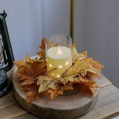 a candle is lit on a wooden tray with leaves