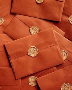 many orange envelopes with gold buttons on them