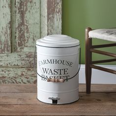 a white canister sitting on top of a wooden table next to a green wall