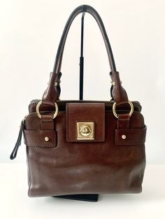 Description:  This vintage Banana Republic bag is beautiful and extremely high quality, which can be seen and felt!  The bag is crafted of genuine dark brown leather and features a gold button flap lock.  It features gold rivet and ring details on the front and back. The top has two zipper compartments with one open compartment in the center. The interior is crafted of brown BR signature fabric and features one zipper pocket.  Are you looking for a high quality bag without the high price tag?  This bag is the one and will not disappoint.  Please review all photos as they are part of the description.  Also, please read through the entire description and if you have any questions please contact us. Size:  It measures approximately 12"L x 4 1/2" D x 9"H with an 8" strap drop.  Condition:  The Daily Use Top Handle Shoulder Bag With Cc Turnlock, Leather Shoulder Bag With Cc Turnlock And Top Handle, Tote Bags With Cc Turnlock Closure For Daily Use, Classic Leather Bag With Cc Turnlock Closure, Elegant Tote Shoulder Bag With Cc Turnlock Closure, Timeless Leather Bag With Cc Turnlock Closure, Leather Tote Shoulder Bag With Cc Turnlock Closure, Leather Shoulder Bag With Cc Turnlock Closure, Formal Leather Shoulder Bag With Cc Turnlock Closure