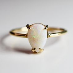 Minimalist modern pear shaped opal solitaire ring. This beautiful Opal Gold Ring was handmade in Melt'm Jewelry Design Studio in California using 9mm x  6.5mm Australian opal featuring on the 14k claw prong setting and 14k yellow gold band.  Perfect for engagement ring. DETAILS ABOUT THE RING, MATERIAL AND STONES Ring Band: 14K YELLOW GOLD Ring Band size: 1.3mm Gemstone: Australian opal Opal size: 9x6.5mm pear cut.  Opal is October birthstone , 14th and 18th Anniversary gemstone. Opal meaning is Opal Meaning, 18th Anniversary, Opal Solitaire Ring, Jewelry Design Studio, October Birthstone Rings, Opal Engagement Ring, Teardrop Ring, Opal Ring Gold, Claw Prong