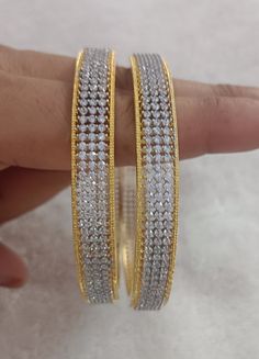 Indulge in the timeless elegance of our CZ diamond bangles, meticulously crafted to captivate with their exquisite beauty. Each bangle features dazzling cubic zirconia stones that mimic the brilliance of diamonds, set in a lustrous metal of your choice. Whether you prefer a delicate, single bangle or a bold, stacked look, our collection offers a range of sizes to suit every wrist. Elevate your style with these stunning bangles, perfect for adding a touch of glamour to any outfit Metal = Gold/Sil Dazzling Sparkling Bangle For Anniversary, Sparkling Dazzling Bangle For Anniversary, Elegant American Diamond Bangle For Anniversary, Sparkling Diamond Bangle Jewelry, Elegant Silver Bangle With American Diamond, White Diamond Cut Bangle Jewelry, Sparkling Diamond Bangle, Sparkling Bangle For Anniversary, Elegant Silver American Diamond Bangle