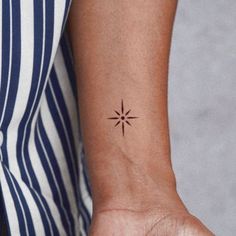 a woman's wrist with a small star tattoo on the left side of her arm