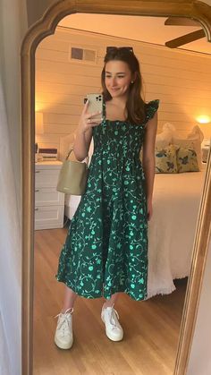 a woman taking a selfie in front of a mirror wearing a green dress and white tennis shoes