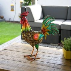 a colorful rooster statue sitting on top of a wooden table