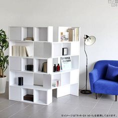 a blue chair sitting in front of a white book shelf next to a potted plant