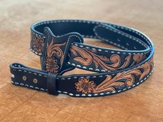 a brown and black leather belt sitting on top of a wooden table