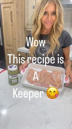 a woman holding a tray of chicken on top of a kitchen counter