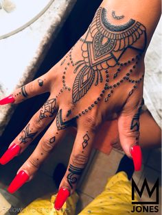 a woman's hand with tattoos and red nails