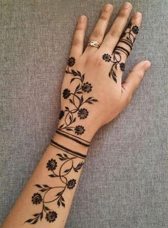 a woman's hand with henna tattoos on her left arm and the wrist