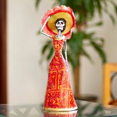 a small figurine with a skeleton on it's head wearing a red dress