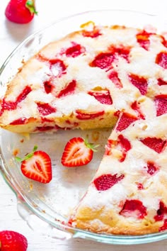 a cake with strawberries on top is cut into slices and served in a glass pie dish