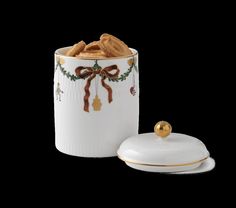 a white canister with a bow on the lid and a plate next to it