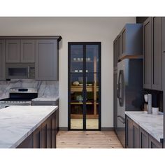 a kitchen with gray cabinets and marble counter tops is seen from the doorway to the dining room