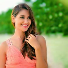 a beautiful young woman in a pink dress posing for the camera with her hand on her shoulder