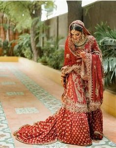 a woman in a red and gold bridal gown is looking down at her cell phone