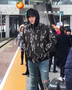 a young man with headphones is standing on the platform next to his luggage and listening to music