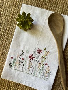 a wooden spoon sitting on top of a table next to a white napkin with flowers