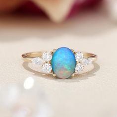 an opal and diamond ring sits on a table