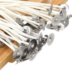 several white and silver toothpicks sitting on top of a wooden board with metal handles