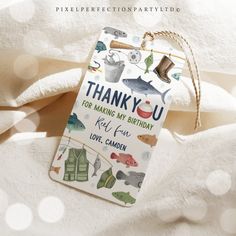 a thank you tag hanging from a string on top of a white sheet with fish and fishing related items