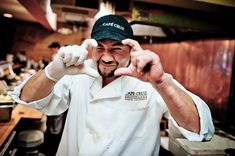 a man in a chef's uniform making the peace sign with his hands