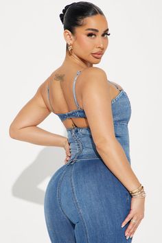 a woman in high waist jeans with her back turned to the camera, wearing a denim jumpsuit