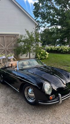 an old black sports car parked in front of a house