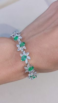 a woman's arm wearing a bracelet with green and white stones