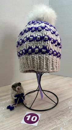 a white and blue hat sitting on top of a table next to a stuffed animal