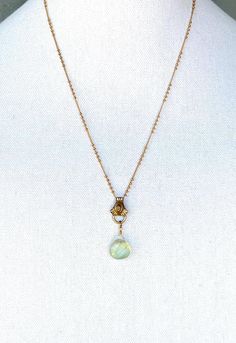 This unique creation is a composite of several carefully selected pieces: the centerpiece is an ornate segment of a vintage necklace; an alternately beaded goldplate chain; and a stunning dew drop of Prehnite stone, believed to open the heart to unconditional love, heal emotional wounds, and promote self-love and forgiveness... Gold Gemstone Drop Necklace For Wedding, Artisan Yellow Gold Teardrop Jewelry, Artisan Brass Jewelry With Gemstone Beads, Artisan Gold Teardrop Pendant Jewelry, Gold Gemstone Teardrop Pendant Jewelry, Gold Teardrop Pendant Jewelry With Gemstone, Bohemian Wire Wrapped Teardrop Pendant Jewelry, Bohemian Gold Emerald Necklace With Gemstone Beads, Jade Pendant Necklace For Wedding