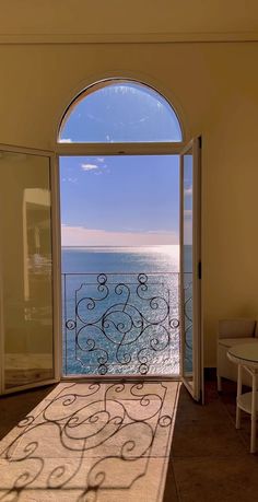 an open door leading to the ocean with a rug on the floor in front of it