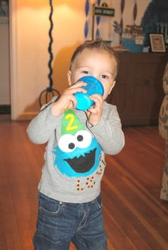 a young boy holding a blue toy in front of his face while standing on a hard wood floor