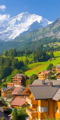 the mountains are covered with snow in the distance, and houses on the hillside have brown shingled roofs