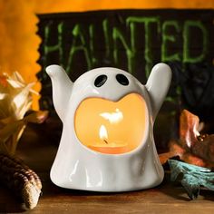 a white ghost tea light holder with a lit candle in the shape of a heart