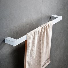 a white towel hanging on the side of a gray wall next to a metal hook