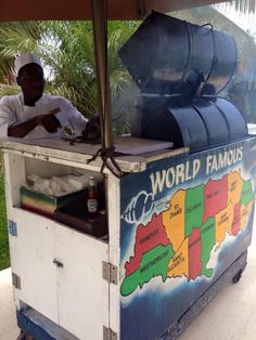 a man sitting at a food cart with a map on the side and words that read world famous